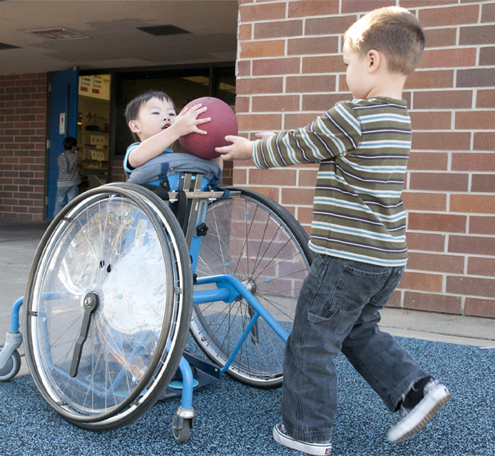 image of student playing ball with other student on blacktop outside.