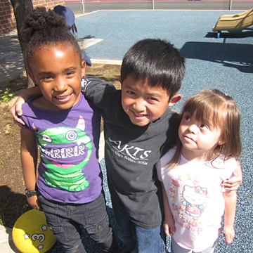 three children standing in a line on a playground